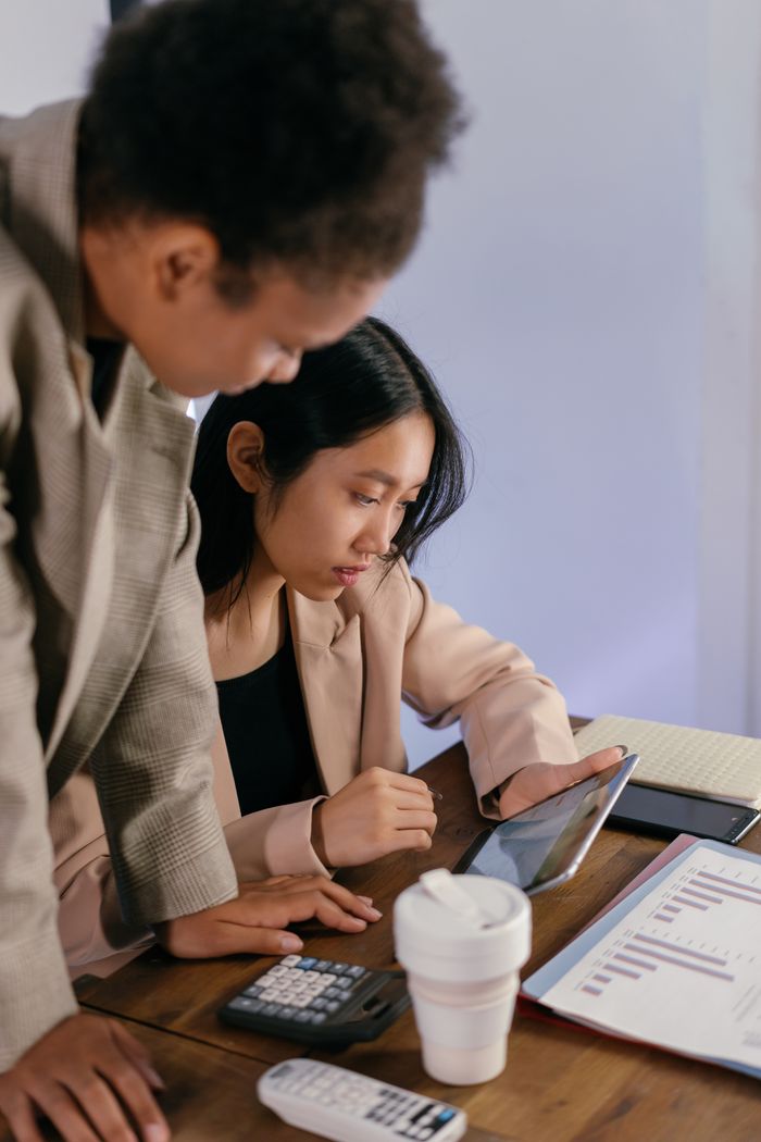 Two businesswomen focused on reviewing financial charts and data in an office setting.